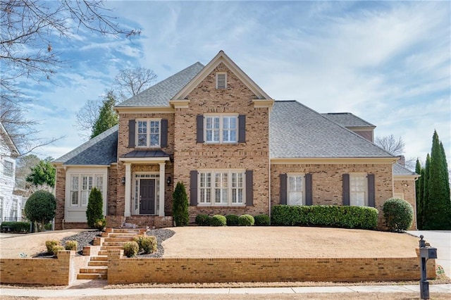 view of front facade with brick siding and a shingled roof