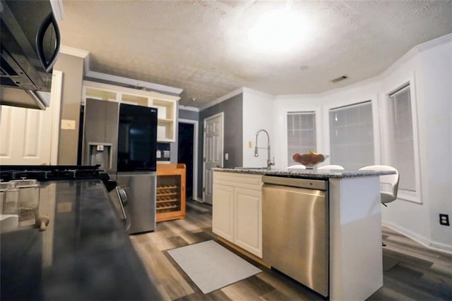 kitchen with appliances with stainless steel finishes, light wood-type flooring, a textured ceiling, crown molding, and sink