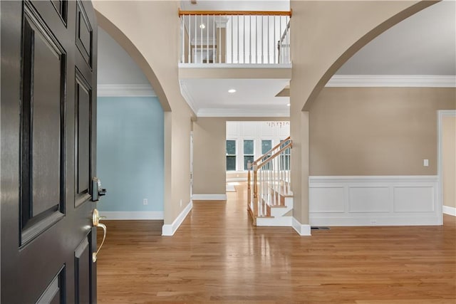 entryway with light wood-type flooring and crown molding