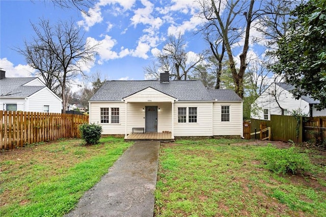 view of front of home featuring a shingled roof, a front lawn, fence, and a chimney