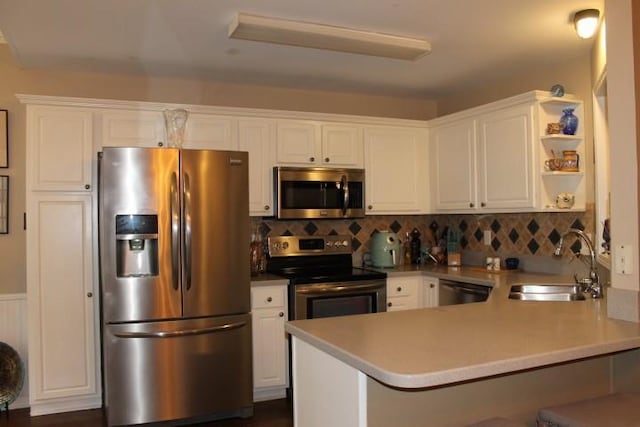 kitchen featuring a sink, open shelves, white cabinetry, appliances with stainless steel finishes, and a peninsula