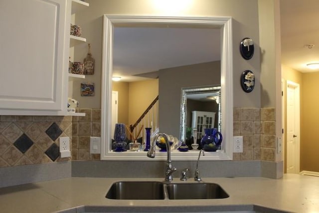 kitchen with a sink, light countertops, decorative backsplash, white cabinets, and open shelves