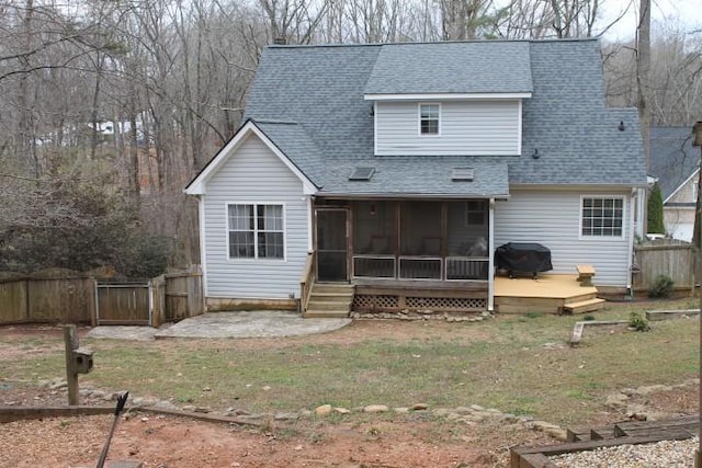 back of property with a deck, fence, a yard, roof with shingles, and a sunroom