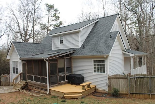 back of house with a wooden deck, a shingled roof, fence, and a sunroom