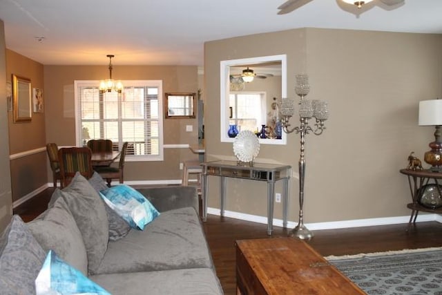 living area featuring baseboards, plenty of natural light, dark wood finished floors, and ceiling fan with notable chandelier