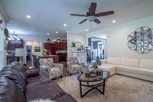 living room featuring crown molding, sink, and ceiling fan with notable chandelier