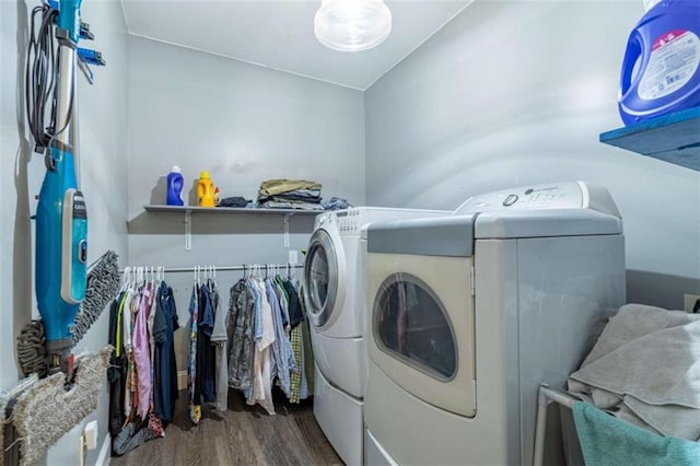 clothes washing area with washing machine and clothes dryer and hardwood / wood-style flooring