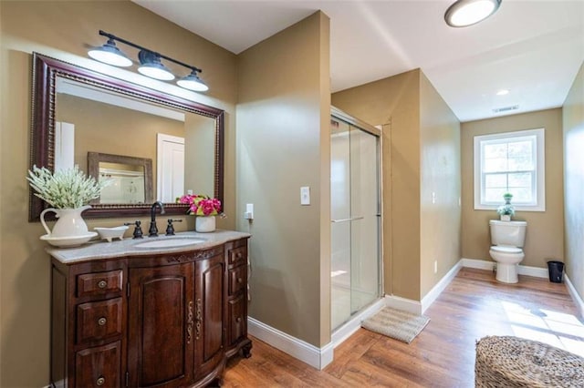 bathroom featuring vanity, wood-type flooring, toilet, and walk in shower