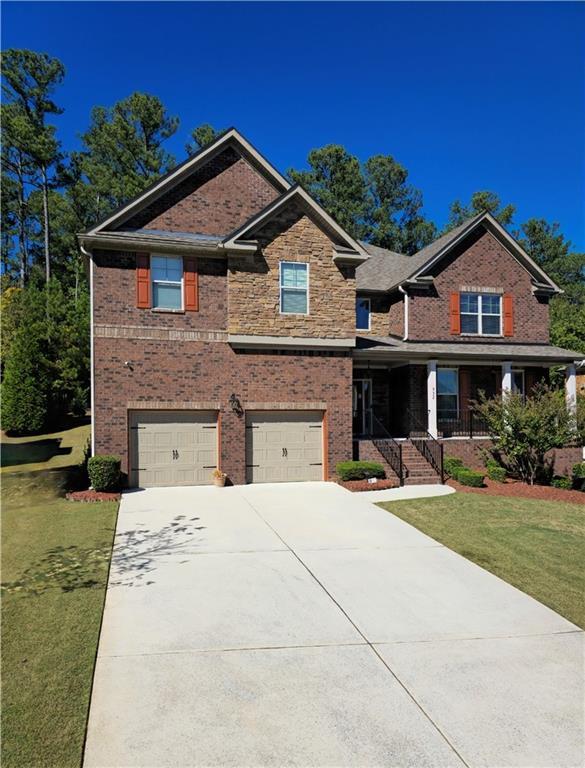 craftsman-style house featuring a garage, covered porch, and a front lawn