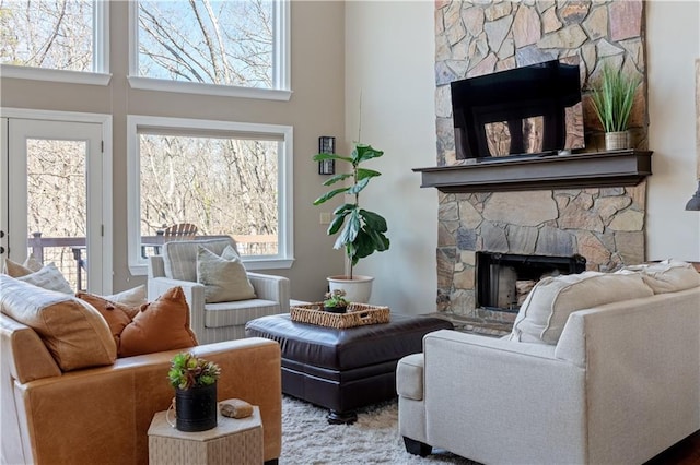 living area with a stone fireplace and a high ceiling