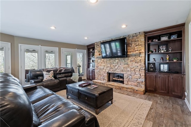 living area featuring recessed lighting, light wood-style flooring, a fireplace, and built in features