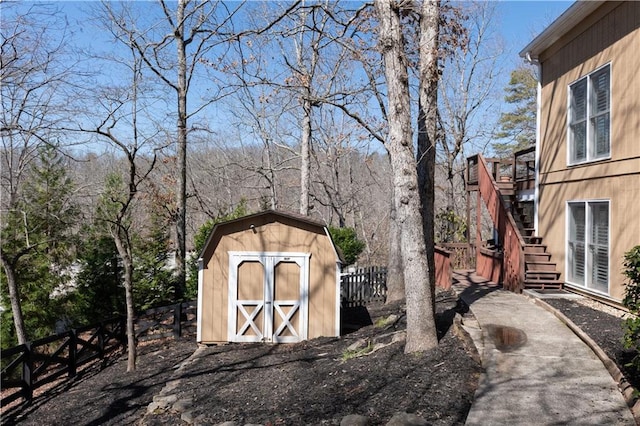 view of shed with stairway and fence