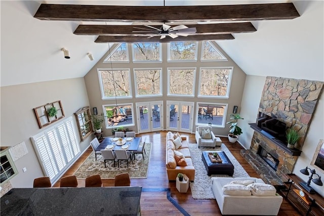 living room featuring wood finished floors, high vaulted ceiling, a fireplace, ceiling fan, and beamed ceiling