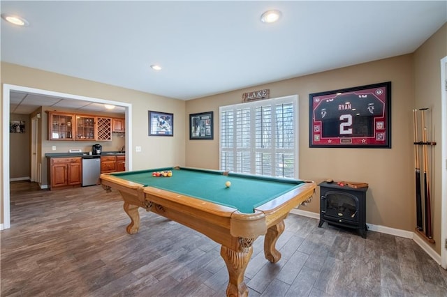 game room featuring baseboards, recessed lighting, wet bar, a wood stove, and wood finished floors