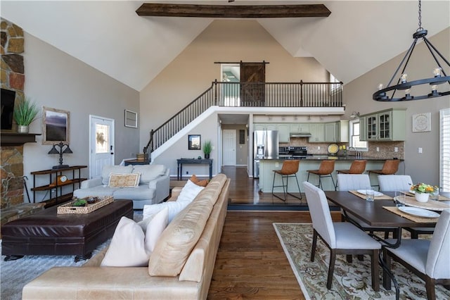 living area featuring dark wood-style floors, a notable chandelier, lofted ceiling with beams, and stairs