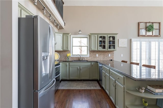 kitchen with backsplash, appliances with stainless steel finishes, a peninsula, and a sink