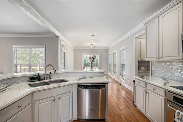 kitchen featuring stainless steel appliances, a sink, healthy amount of natural light, light wood finished floors, and ornamental molding