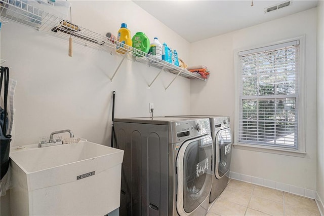 laundry room featuring washing machine and dryer, baseboards, and light tile patterned floors
