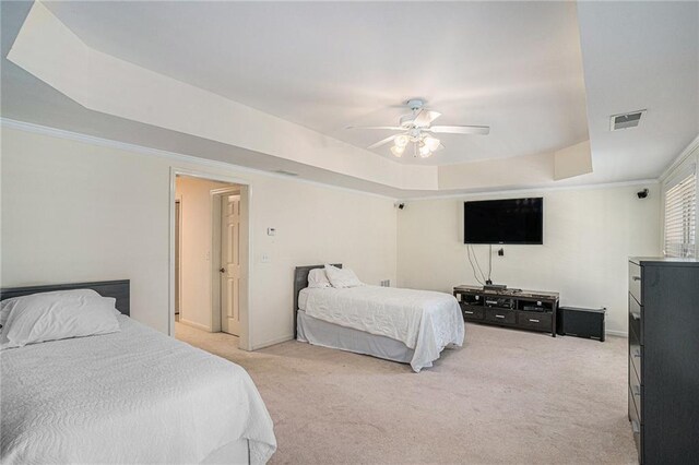 bedroom with a tray ceiling, light carpet, ceiling fan, crown molding, and baseboards