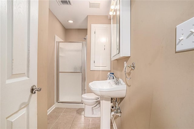 bathroom featuring a shower stall, tile patterned floors, toilet, baseboards, and a sink