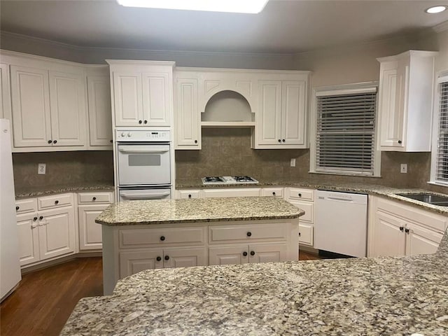 kitchen featuring dark wood-style floors, white appliances, light stone counters, and white cabinets