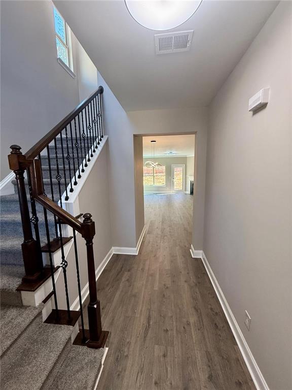 hall featuring stairway, wood finished floors, visible vents, and baseboards