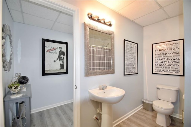 bathroom featuring a sink, wood finished floors, a paneled ceiling, and baseboards