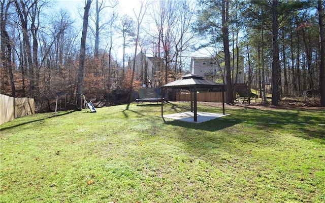 view of yard with a gazebo, a trampoline, a playground, and fence