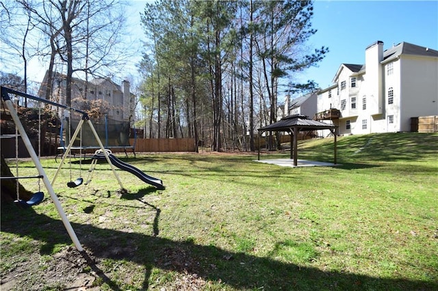 view of yard with a trampoline, a playground, fence, and a gazebo