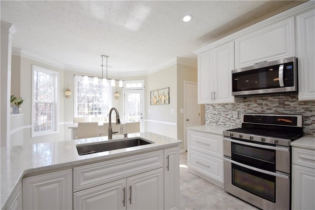 kitchen with stainless steel appliances, a sink, white cabinets, tasteful backsplash, and crown molding