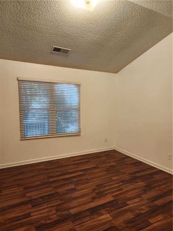 empty room featuring a textured ceiling and dark hardwood / wood-style floors