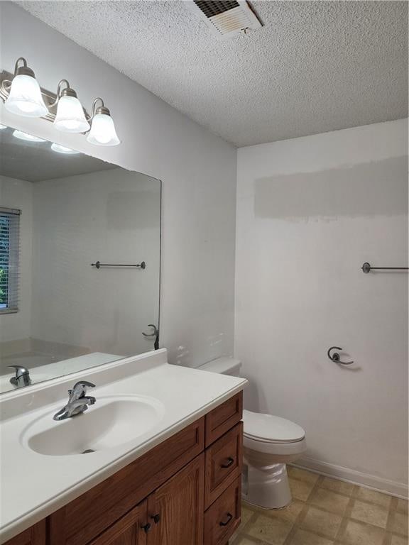 bathroom featuring a textured ceiling, vanity, and toilet