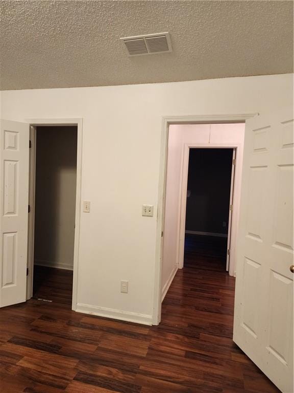 empty room with a textured ceiling and dark hardwood / wood-style floors