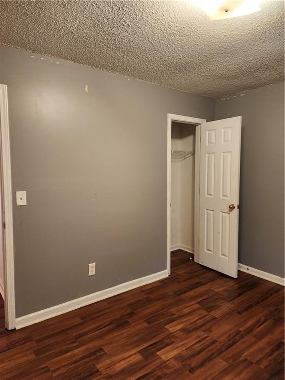 835 Amelia Grove Ln, Lawrenceville, GA 30045 - unfurnished bedroom featuring a textured ceiling, baseboards, a closet, and dark wood-style floors