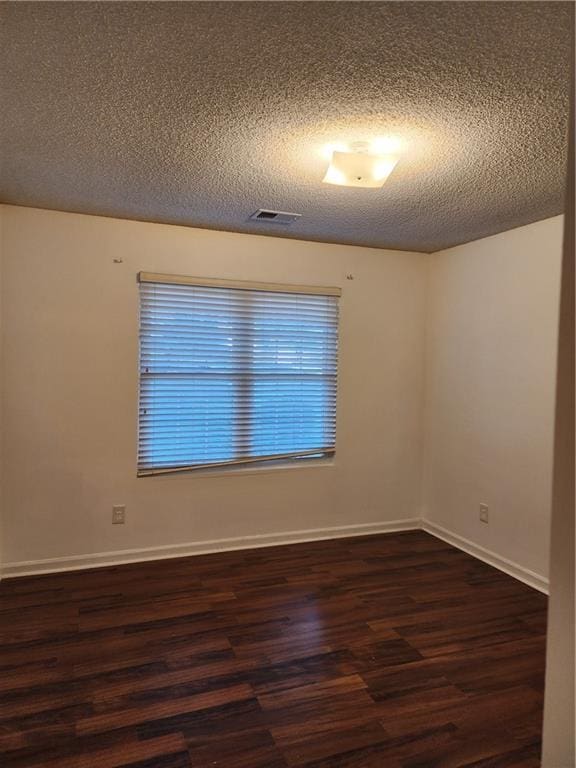 unfurnished room with a textured ceiling and dark hardwood / wood-style flooring