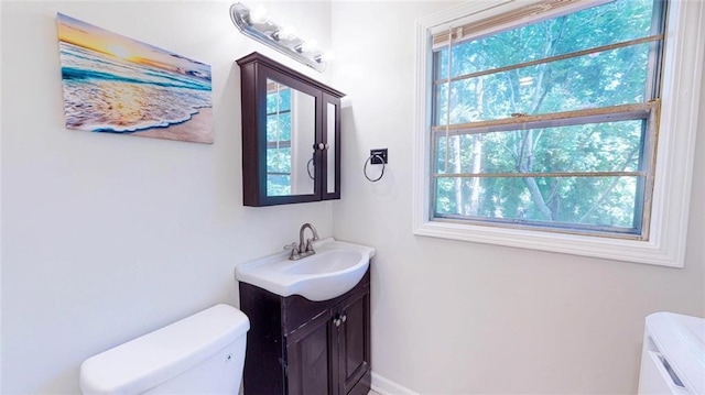 bathroom featuring toilet, vanity, and plenty of natural light