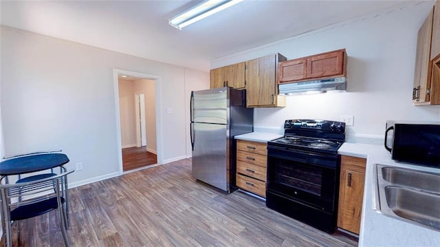 kitchen featuring black appliances, dark hardwood / wood-style floors, and sink