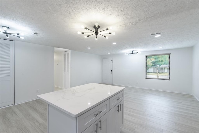 4922 Glenside Ct, Stone Mountain, GA 30088 - kitchen with light wood-style flooring, a textured ceiling, a kitchen island, open floor plan, and a chandelier