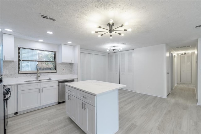 4922 Glenside Ct, Stone Mountain, GA 30088 - kitchen with stainless steel dishwasher, a sink, a chandelier, a textured ceiling, and light wood-type flooring