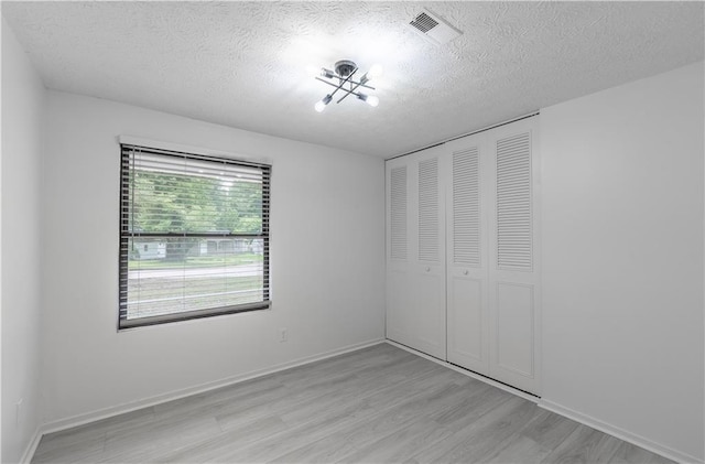 4922 Glenside Ct, Stone Mountain, GA 30088 - unfurnished bedroom featuring light wood-style flooring, a textured ceiling, a closet, and baseboards