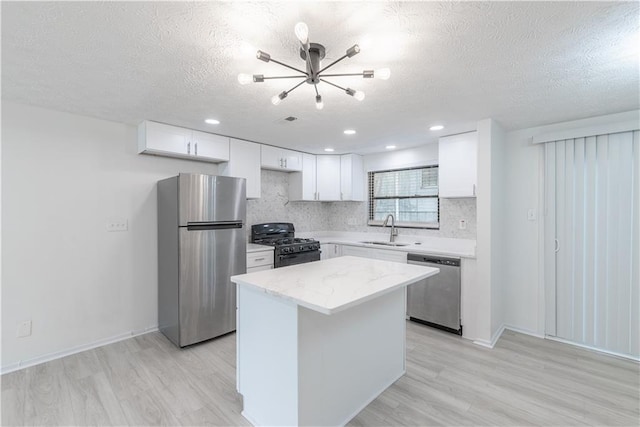 4922 Glenside Ct, Stone Mountain, GA 30088 - kitchen featuring stainless steel appliances, a sink, a chandelier, a textured ceiling, and light wood-style flooring