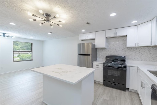 4922 Glenside Ct, Stone Mountain, GA 30088 - kitchen with gas stove, freestanding refrigerator, light wood-style floors, a kitchen island, and a textured ceiling