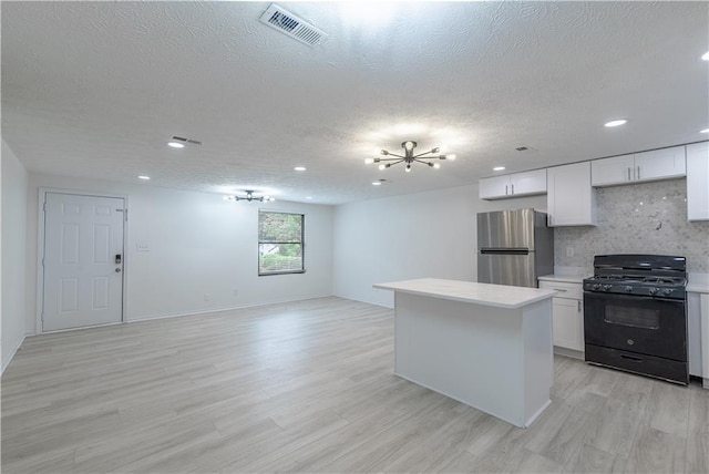 4922 Glenside Ct, Stone Mountain, GA 30088 - kitchen with black gas range oven, freestanding refrigerator, a textured ceiling, light wood-style floors, and tasteful backsplash