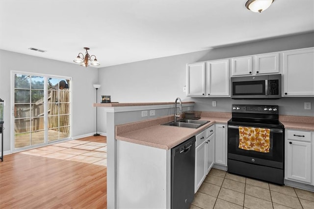 kitchen with black appliances, visible vents, white cabinetry, and a sink