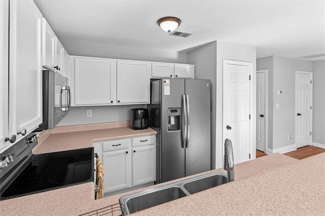 kitchen featuring light countertops, electric range, white cabinets, a sink, and stainless steel fridge with ice dispenser