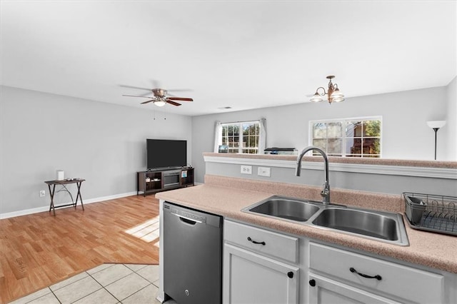 kitchen with light tile patterned floors, light countertops, stainless steel dishwasher, white cabinetry, and a sink