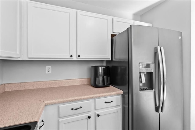 kitchen with white cabinetry, stainless steel refrigerator with ice dispenser, light countertops, and stove