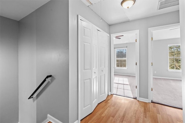 hall featuring visible vents, plenty of natural light, an upstairs landing, and baseboards