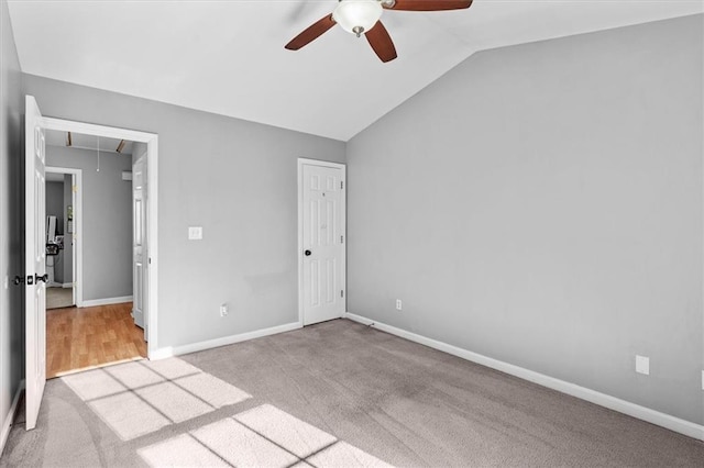 unfurnished bedroom featuring vaulted ceiling, carpet, attic access, and baseboards