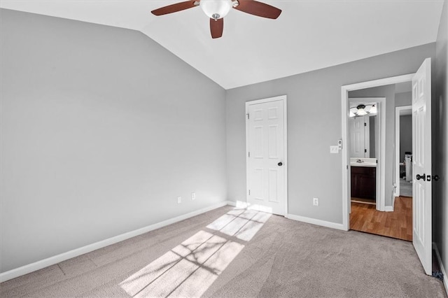 unfurnished bedroom featuring a sink, carpet flooring, a ceiling fan, vaulted ceiling, and baseboards